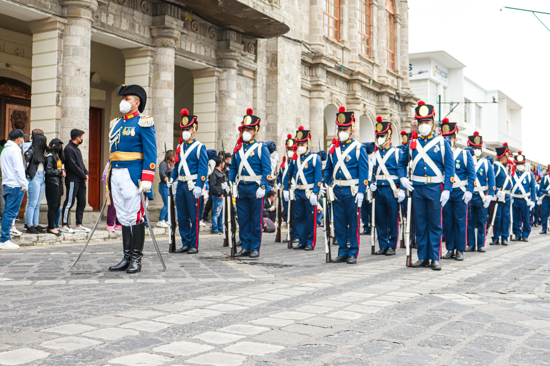 Ecuadorian soldiers in ceremonial uniforms stand in formation during a parade, showcasing tradition and discipline.