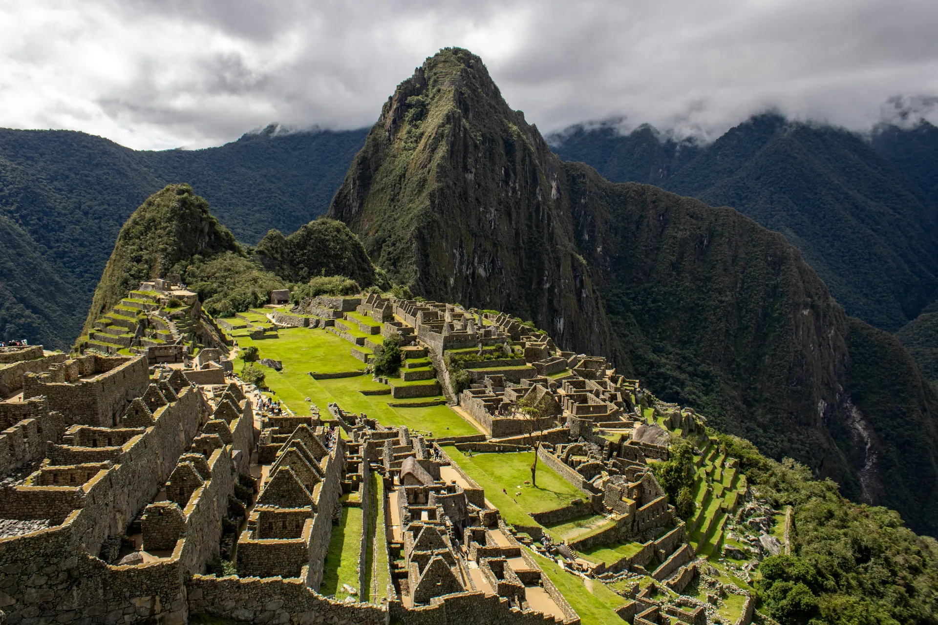A breathtaking daytime view of the ancient Incan city of Machu Picchu, set against lush mountains.